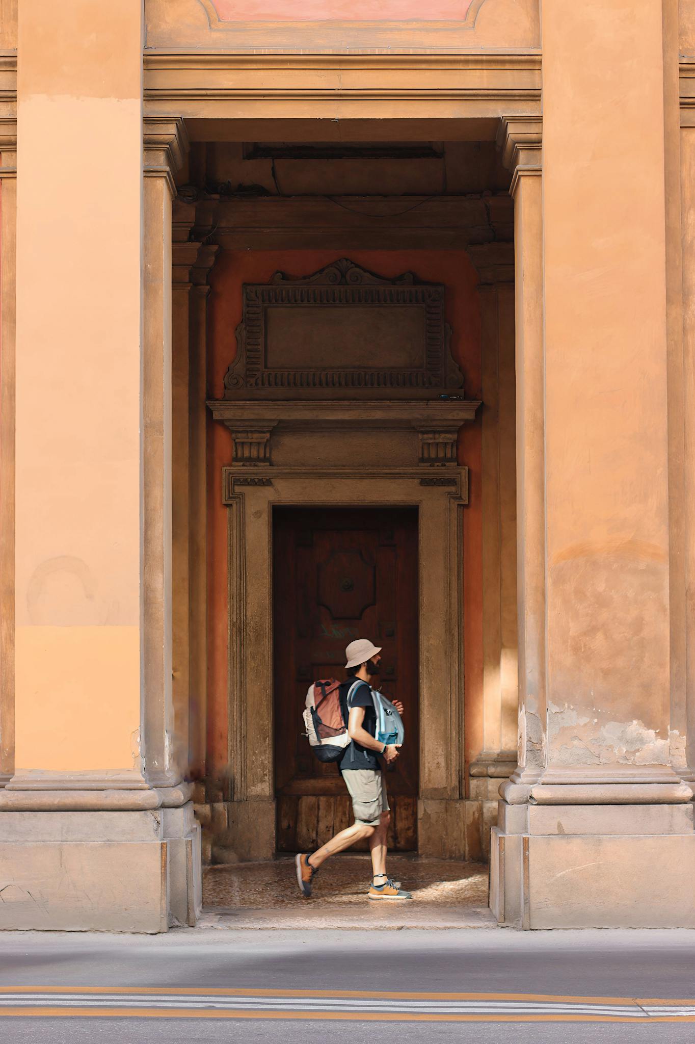 A backpacker walks past historical architecture in Bologna, Italy.
